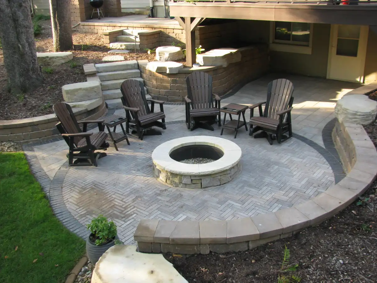 Circular herringbone paver patio with fire pit and Adirondack chairs