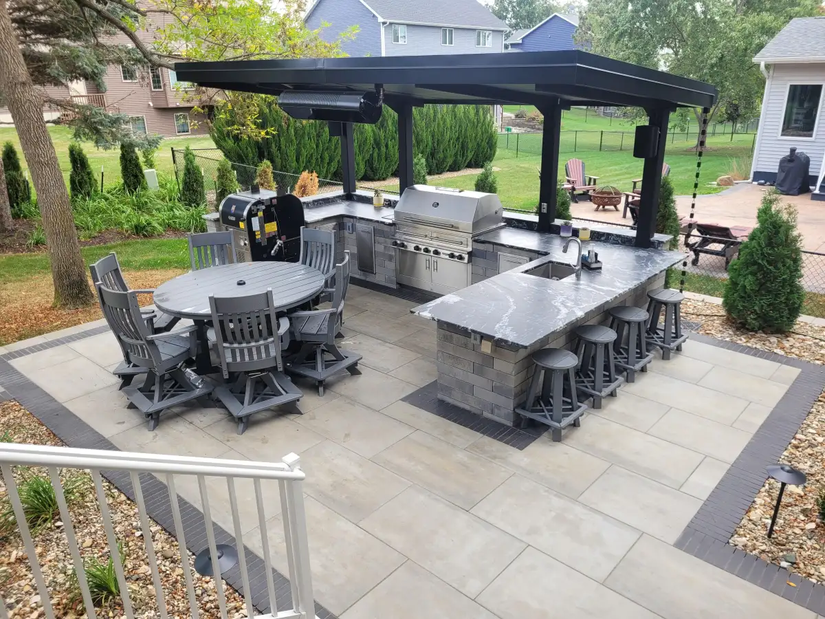 Covered outdoor kitchen pavilion with stone pillars and paver patio in Iowa