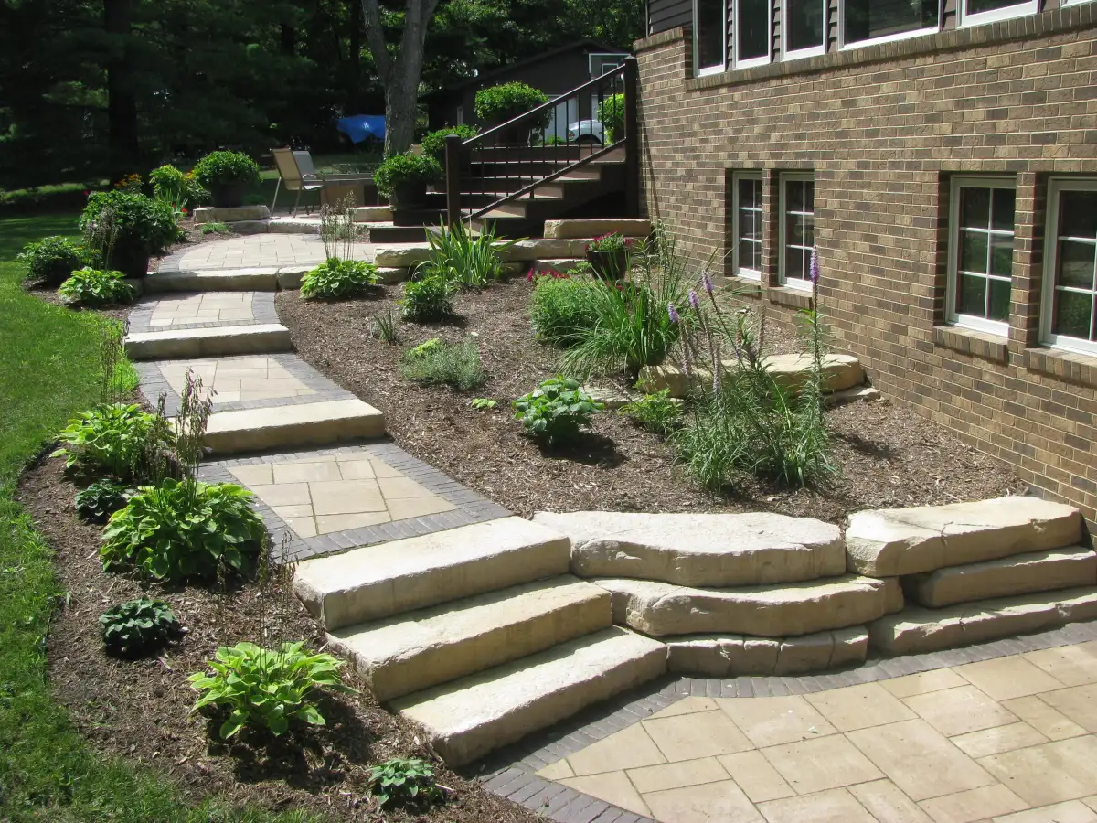 Paver walkway with natural stone steps and colorful flower beds