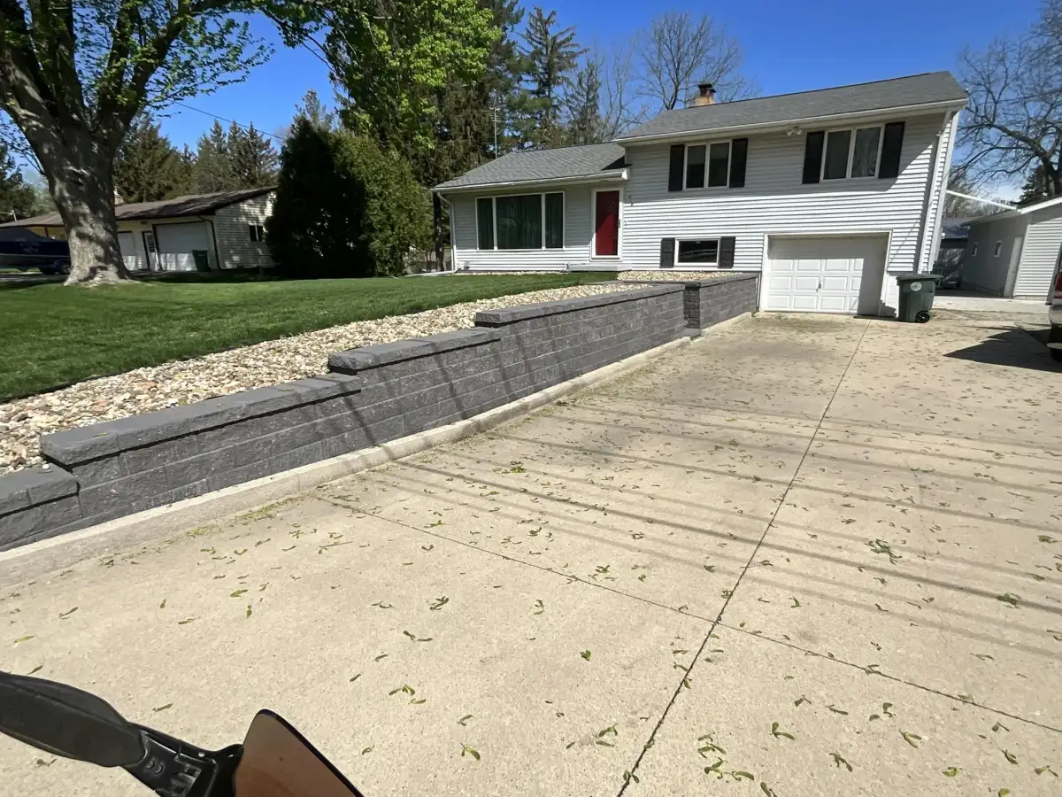 Massive block retaining wall on rural property with farmhouse and pond